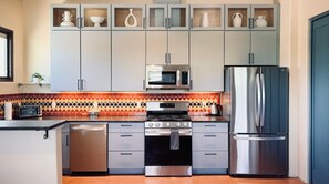 Eine moderne Küche mit Mikrowelle, Backofen, Kühlschrank und einem Schrank mit Dekorationselementen.