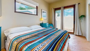 Een slaapkamer met een bed, een raam, een nachtkastje en uitzicht op buiten.
