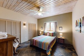 A bedroom with a bed, wooden ceiling, and a window with curtains.