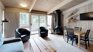A cozy living room with a wooden ceiling, a fireplace, a TV, and a dining area. - Sierra Del Sol 30 - Hot Tub, Walk to Lifts & Town (Taos Ski Valley)
