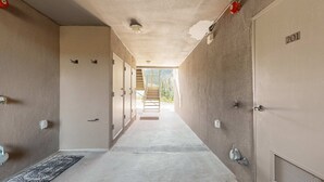 Passadís amb armaris, una porta amb el número '201' i una escala que mena a una zona exterior.
