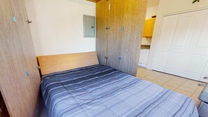 Habitació amb llit, armari de fusta i porta blanca.