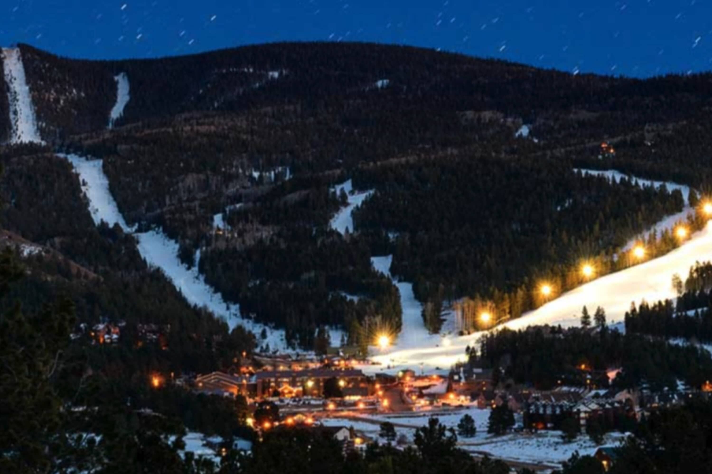 Ein schneebedeckter Berg mit einem Skigebiet und einer Stadt im Tal.
