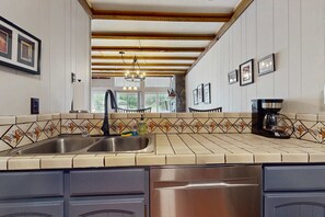 A kitchen with a double sink, a coffee maker, and a tiled backsplash. - Timbers Five - Walk to Ski, Hike, Bike & Dining (Angel Fire)