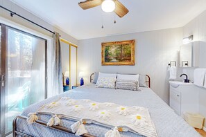 A bedroom with a bed, a painting, a window with curtains, a bedside table, and a nightstand. - Pinetree 213 - Walk to Ski, Hike, Bike & Dining (Angel Fire)