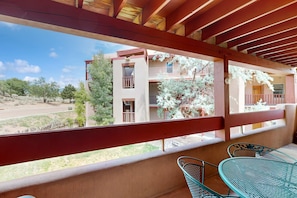 A balcony with a view of a building, a metal chair, and a table. - Cielo Grande - Close to Plaza & Railyard with AC (Santa Fe)