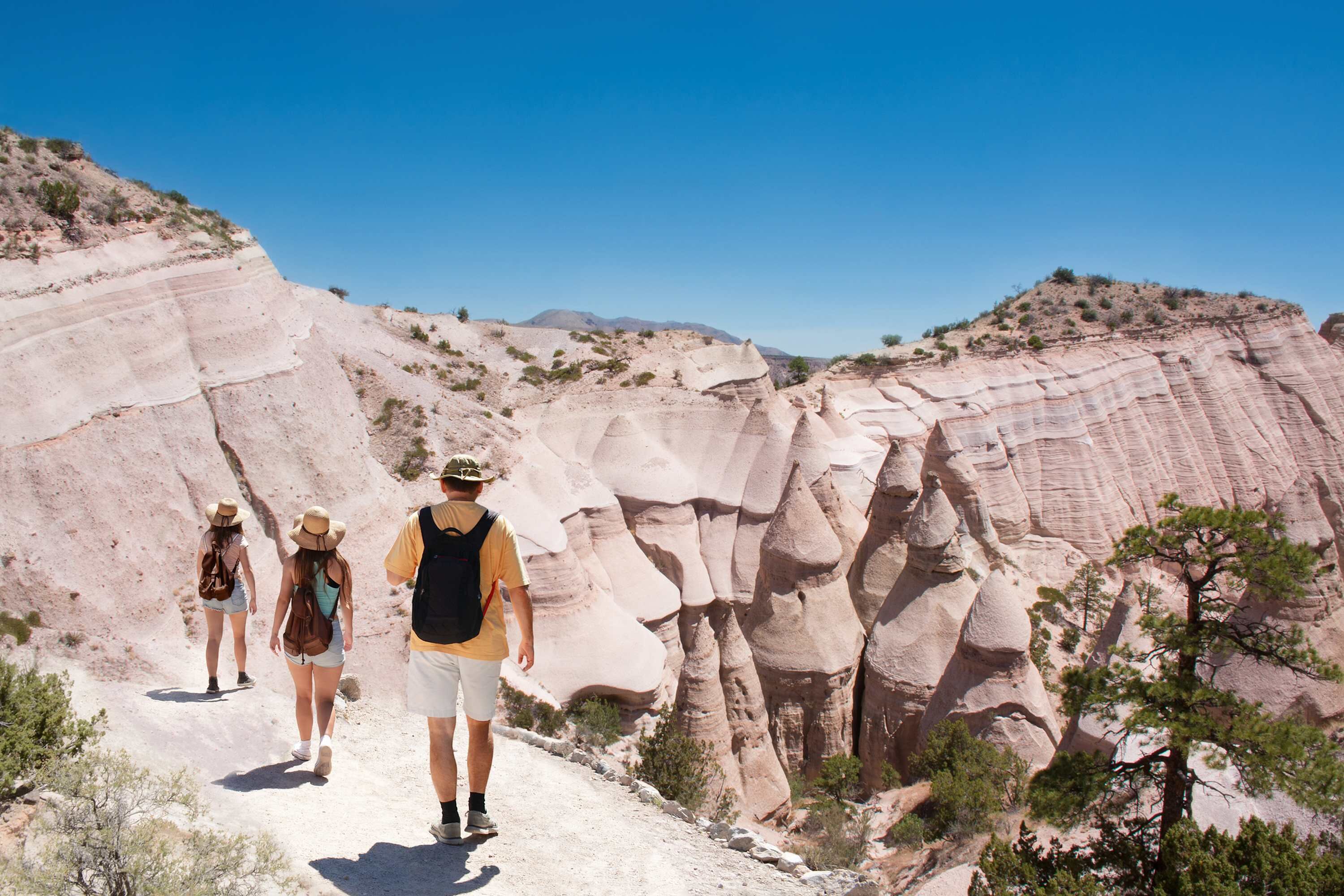 A group of people hiking on a rocky trail surrounded by layered rock formations.