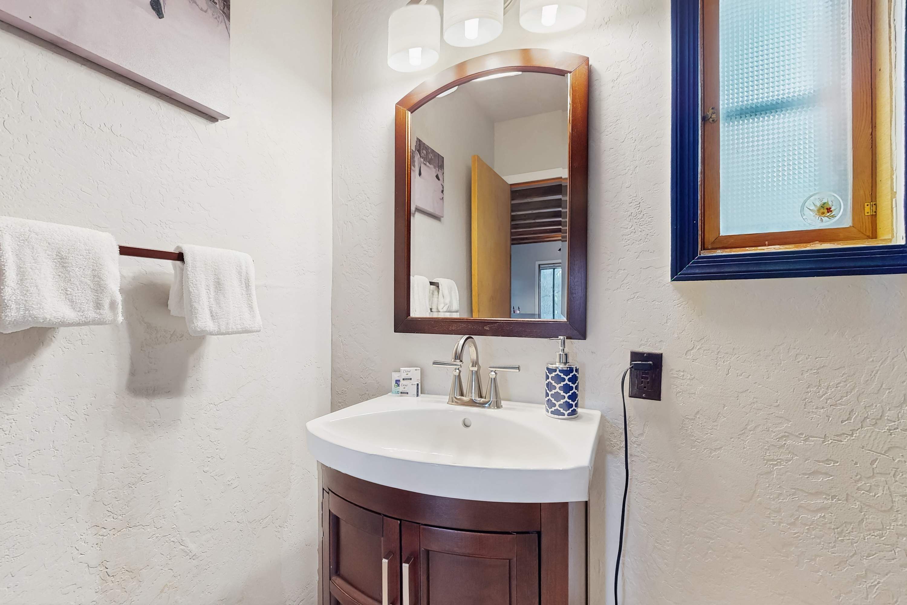 Een badkamer met een wit wastafel, een spiegel en een handdoekhouder.
