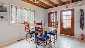 A dining area with a wooden table and chairs, large windows, and a wooden ceiling. - Bigfoot Lodge - Mountain Views & Multiple Decks (Angel Fire)