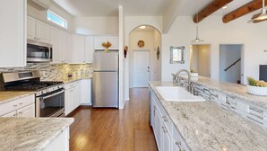 Una cocina moderna con armarios blancos, una estufa de acero inoxidable y una encimera de granito.