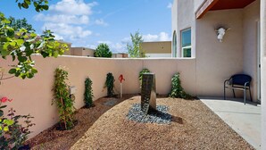 Un patio con una fuente de agua, una silla y una decoración de cráneo montada en la pared.