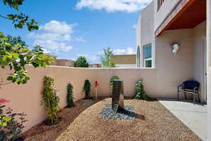 A courtyard with a water feature, a chair, and a wall-mounted skull decoration. - Shalako Adventures - Modern Adobe & Near Downtown (Santa Fe)