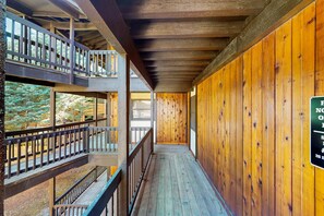 A wooden corridor with a balcony on the left and a sign on the right. - Snowfire 205A - Walk to Ski, Hike, Bike & Dining (Angel Fire)