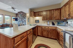 A kitchen with wooden cabinets, a dishwasher, a microwave, and a toaster. - Gold Creek 208 - Walk to Lifts, Slope Views & Deck (Angel Fire)