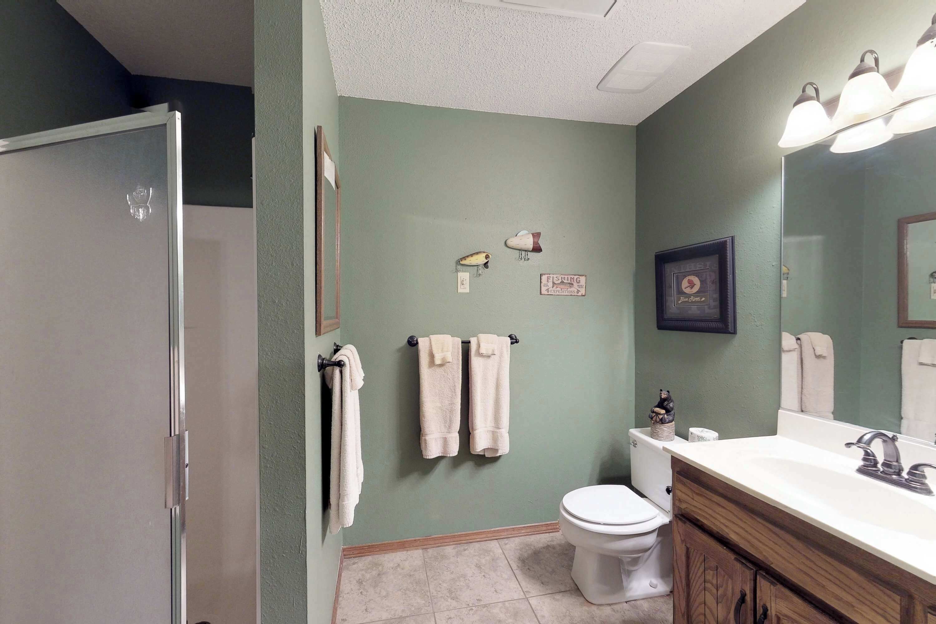 A bathroom with a toilet, sink, and a shower area.