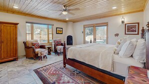 A bedroom with a wooden ceiling, a bed with white bedding, a chair, a rug, and a wooden wardrobe. - Casa de Rufina - Mountain Views, Firepit & Pets (Arroyo Seco)