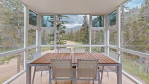 A room with a wooden table and chairs, large windows, and a view of a forest and mountains. - Kachina Ridge Dreams - Walk to Lifts & Huge Views (Taos Ski Valley)