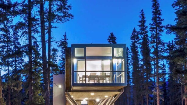 A modern building with a glass facade, surrounded by trees, and a road with light trails. - Kachina Ridge Dreams - Walk to Lifts & Huge Views (Taos Ski Valley)