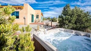Uma área de spa com hidromassagem, cercada por uma casa com vista para as montanhas.