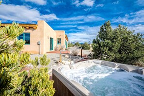 Ein Wellnessbereich mit Whirlpool, umgeben von einem Haus mit Bergblick.