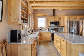 Eine geräumige Küche mit Holzausstattung, einem Edelstahlkühlschrank und einem großen Fenster.