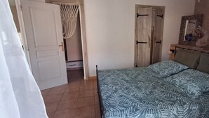 A bedroom with a bed, a door, and a wall with a picture frame. - Havre de Paix next to the coast, 5 minutes from Petit-havre beach (Le Gosier)