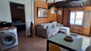 A compact living space with a washing machine, a sofa, a dining table, and a window with curtains. - Havre de Paix next to the coast, 5 minutes from Petit-havre beach (Le Gosier)