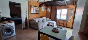 A compact living space with a washing machine, a sofa, a dining table, and a window with curtains. - Havre de Paix next to the coast, 5 minutes from Petit-havre beach (Le Gosier)