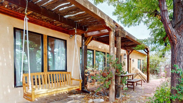 A wooden porch with a bench, a swing, and a stone pathway.