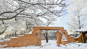 A snow-covered outdoor area with a rustic stone structure, possibly a garden or courtyard.
