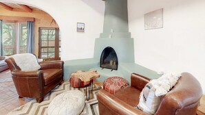 A cozy living room with a fireplace, leather sofas, and a wooden ceiling.