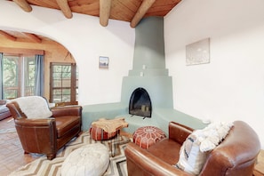 Una sala de estar acogedora con chimenea, sofás de cuero y techo de madera.