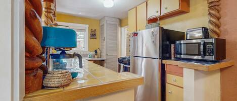 A kitchen with a built-in microwave, refrigerator, and a wooden countertop.