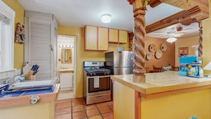 Una cocina con estufa, horno, refrigerador, armarios de madera y piso de baldosas.