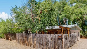 Una cabaña rústica con valla de madera, rodeada de árboles.