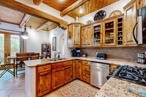 Une cuisine dotée de meubles en bois, d’un plan de travail en granit, d’un lave-vaisselle, d’une cuisinière et d’un coin repas avec une table et des chaises.