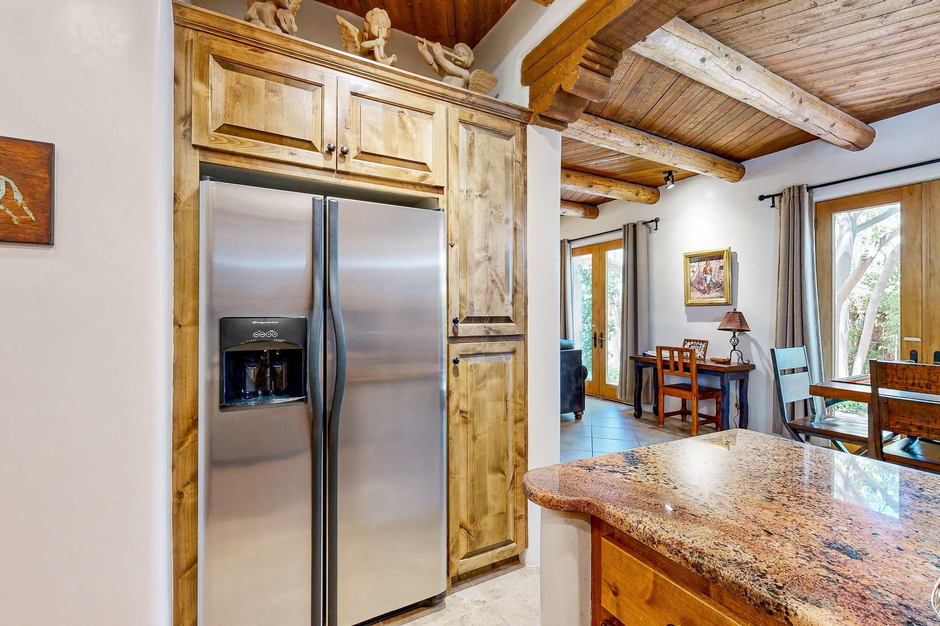 Una cucina con mobili in legno, un frigorifero in acciaio inossidabile, un dispenser per l'acqua e un piano di lavoro in granito.