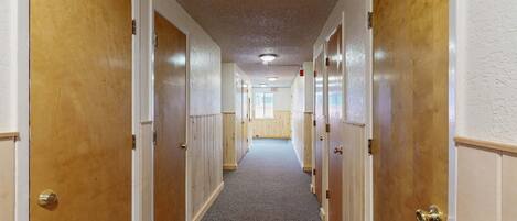 A hallway with wooden doors, carpeted floor, and a ceiling with recessed lighting.