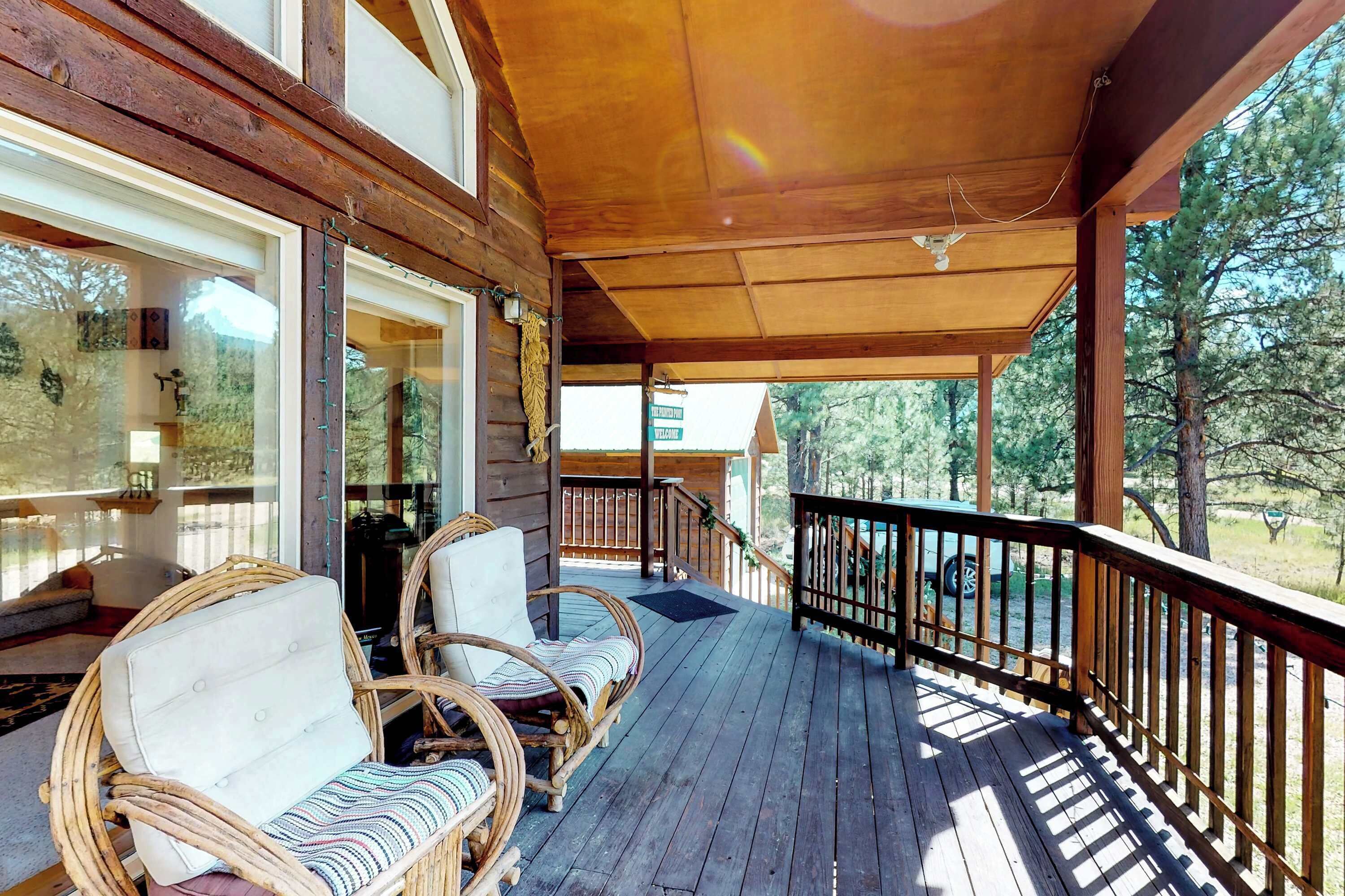 A wooden deck with wicker chairs and a view of the surrounding forest.