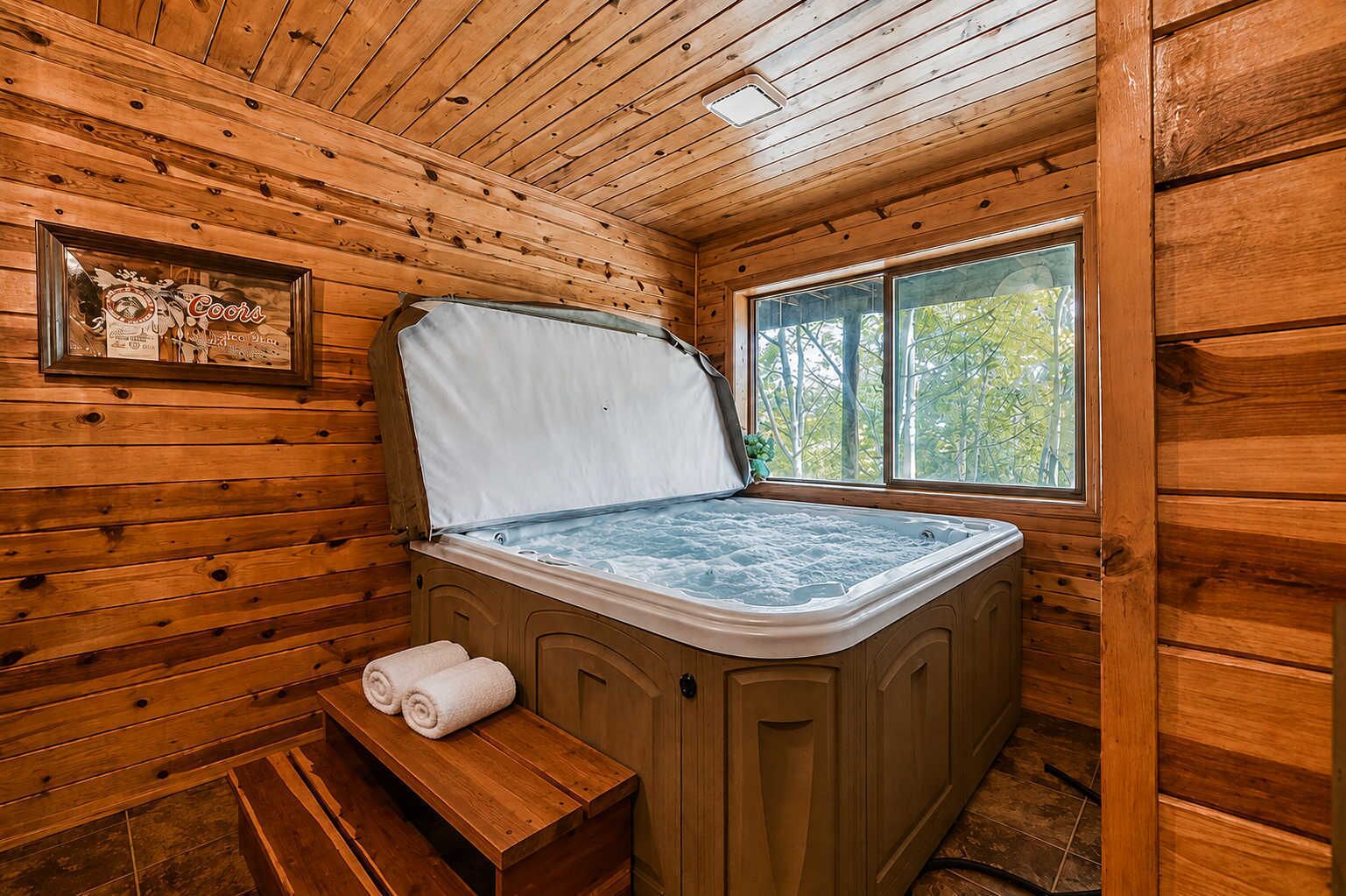 Een houten hut met een jacuzzi, een bankje en een raam met uitzicht op bomen.