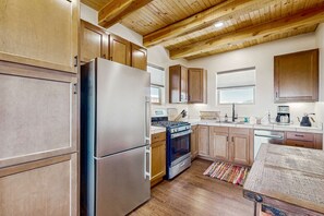 Eine Küche mit Holzausstattung, einem Edelstahlkühlschrank, einem Backofen und einem Holztisch.