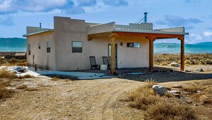 Ein modernes Haus mit Flachdach, überdachter Veranda und Blick auf den Ozean.