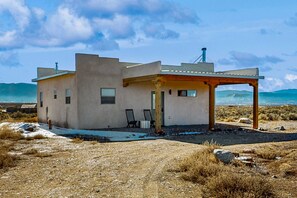 Ein modernes Haus mit Flachdach, überdachter Veranda und Blick auf den Ozean.
