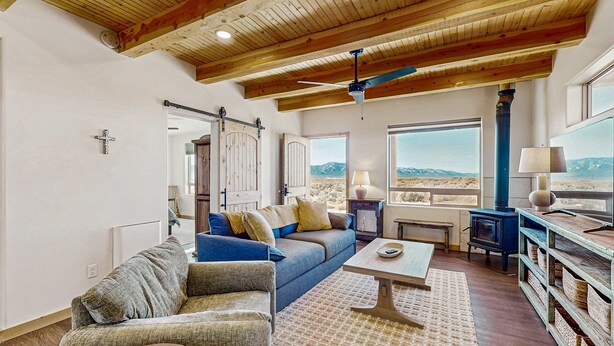 Ein Wohnzimmer mit Holzboden, einer Couch, einem Couchtisch und Bergblick.
