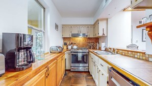 A compact kitchen with wooden cabinets, a coffee maker, a toaster, and a dishwasher. - Casa Oeste - Walk to Plaza, Shaded Patio, Dog OK (Santa Fe)