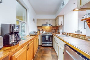 A compact kitchen with wooden cabinets, a coffee maker, a toaster, and a dishwasher. - Casa Oeste - Near Plaza with Santa Fe Charm (Santa Fe)