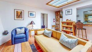 A living room with a sofa, armchair, and bookshelf. - Casa Oeste - Walk to Plaza, Shaded Patio, Dog OK (Santa Fe)
