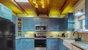 A kitchen with blue cabinets, a black refrigerator, a stove, and a microwave.