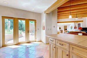 A spacious kitchen with wooden cabinets, a large island, and a sliding glass door leading to an outdoor area. - Casa del Suenos - Steps to Plaza - Patio & Garden (Taos)