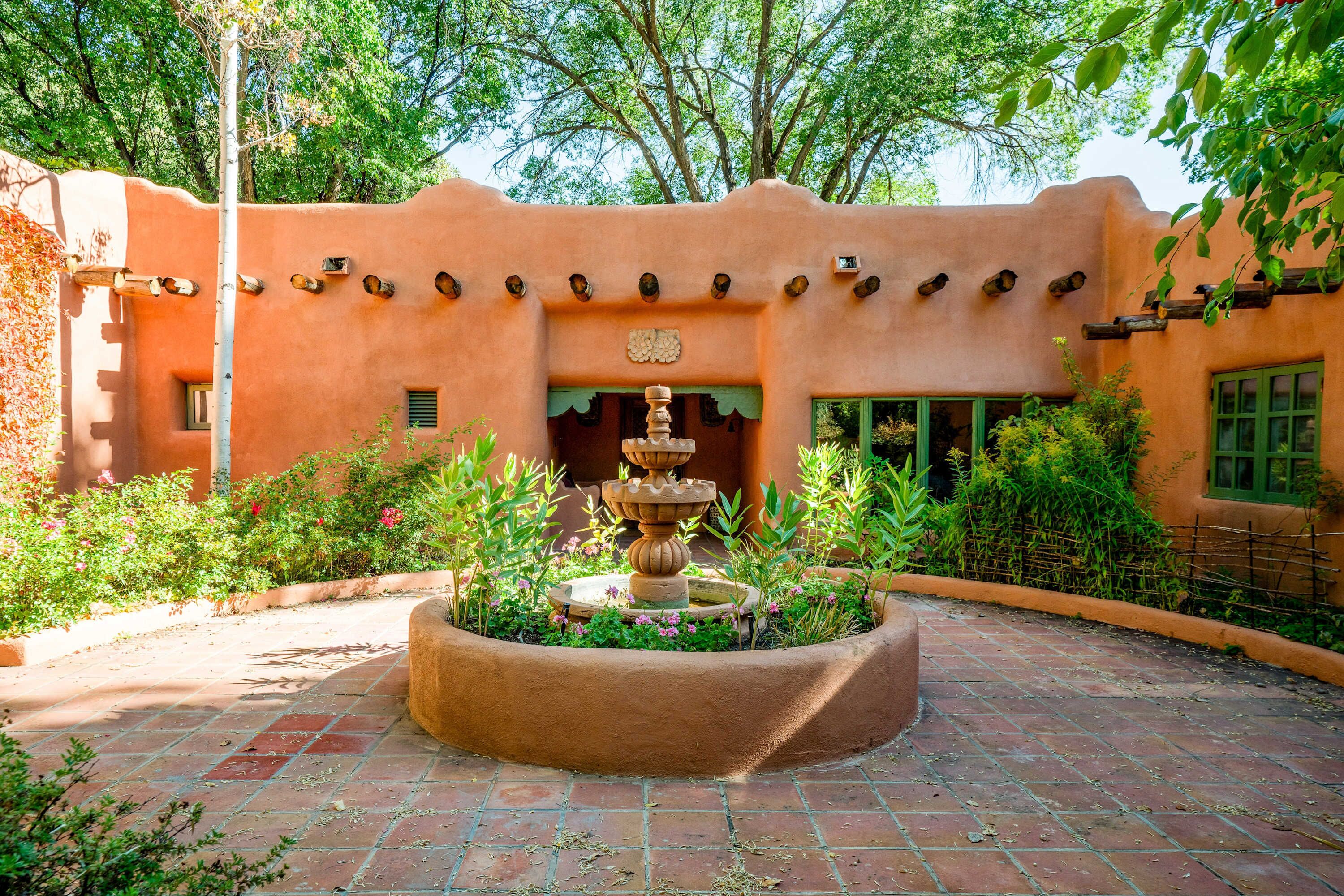 A courtyard with a central fountain, surrounded by a brick pathway and lush greenery.